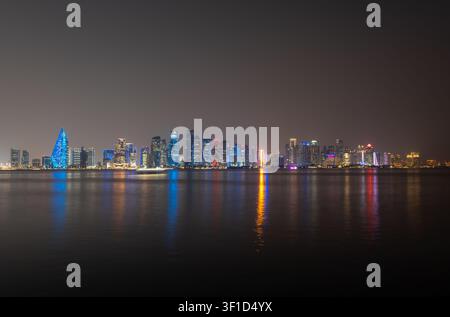 Doha, Qatar - 11 novembre 2025: Una vasta vista panoramica a lunga esposizione dello skyline illuminato di Doha di notte, che mostra grattacieli moderni. Foto Stock
