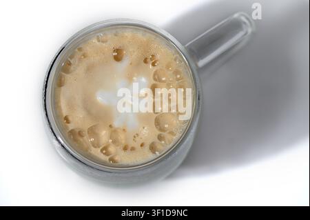 Questa fotografia in studio ad angolazione alta mostra una vista dall'alto di una tazza di vetro ripiena di un cappuccino appena preparato, completo di una schiuma di latte distintiva Foto Stock