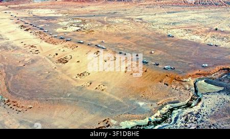 Vista aerea di un campeggio per roulotte nel deserto accanto a un bordo di canyon. Una vista aerea mostra roulotte e veicoli sparsi su un vasto altopiano desertico accanto a un'erosione Foto Stock