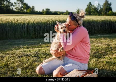 Donna spensierata che bacia il suo cane. Amicizia e amore tra uomo e cane. Momento felice con l'animale domestico all'aperto Foto Stock