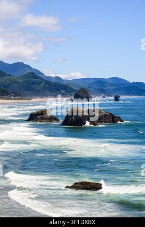Pilastri marini tra le onde costiere a Cannon Beach sulla costa dell'Oregon in estate Foto Stock