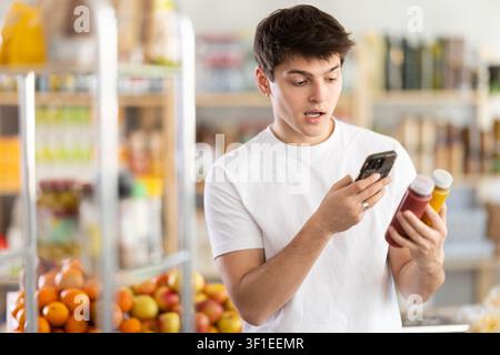 La donna che acquista scansiona il codice QR sul flacone di frullato con il suo smartphone Foto Stock