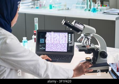 Donna musulmana che analizza un campione di sangue in laboratorio Foto Stock