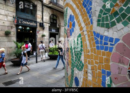 Muro a mosaico trencadís colorato accanto a una strada pedonale nel Quartiere Gotico di Barcellona, Spagna. Foto Stock
