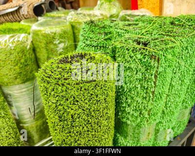 Vista ravvicinata di erba artificiale ordinatamente arrotolata, che mostra la sua texture verde vibrante e fibre dense, perfetta per varie applicazioni Foto Stock