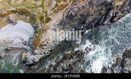 Vista aerea di una persona in giacca rossa che esplora una costa impervia Foto Stock
