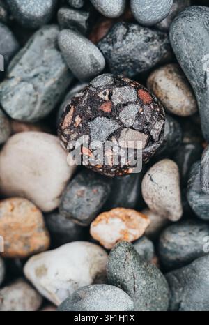La pietra conglomeratica si trova tra le rocce naturali della spiaggia Foto Stock