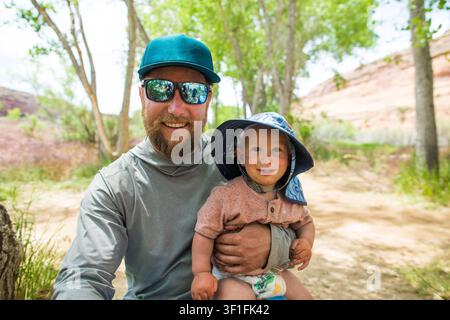 Padre felice che tiene il suo bambino sorridente all'aperto Foto Stock