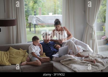 Famiglia di quattro persone che si rilassano insieme su un divano Foto Stock