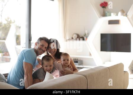 Famiglia felice di quattro persone che sorride per una foto a casa Foto Stock