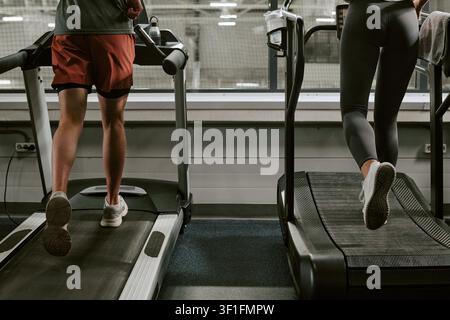 Uomo e donna atletici che corrono su tapis roulant per l'allenamento fisico Foto Stock