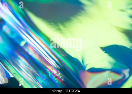 Sfondo astratto con materiale olografico e riflessi di luce iridescenti. Blu, verdi e viola vibranti creano un'atmosfera dinamica e futuristica Foto Stock
