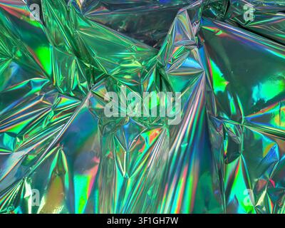 Texture di lamina olografica verde increspata con riflessi arcobaleno vibranti, che crea una superficie visivamente dinamica e artificiale. Ideale per la moda astratta Foto Stock
