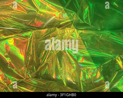 Primo piano di una pellicola olografica accartocciata che crea colori vivaci arcobaleno ed effetti scintillanti. Transizione sfumata liscia da giallo a verde. Perfetto Foto Stock
