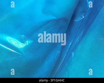 Primo piano di tessuto blu strutturato con riflessione di luce brillante. Crea uno sfondo astratto liscio e fluente per concetti di benessere e stile di vita, enfatizza Foto Stock