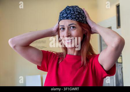 Donna sorridente che lavora in un servizio di autolavaggio e indossa un bandana Foto Stock