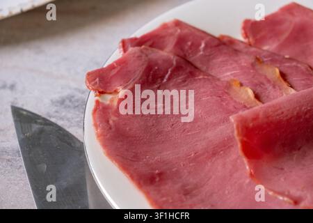 Prima vista di fette di carne essiccata servite su un piatto di ceramica bianca Foto Stock