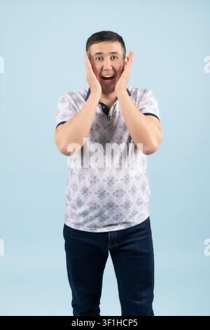 Giovane uomo sorpreso con le mani sulle guance che guarda scioccato in un professionale... Foto Stock