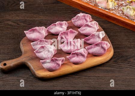 Dumplings di verdure colorati crudi e freschi su piatti, Jiaozi cinesi congelati Foto Stock