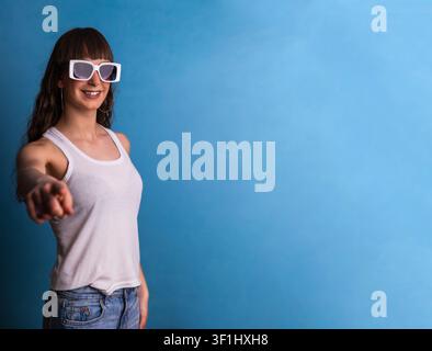 Giovane donna che indica la fotocamera indossando occhiali da sole Foto Stock