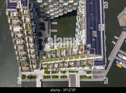 Vista aerea dell'edificio Sluishuis con la sua architettura geometrica unica, terrazze sul tetto, pannelli solari e l'acqua circostante ad Amsterdam Foto Stock