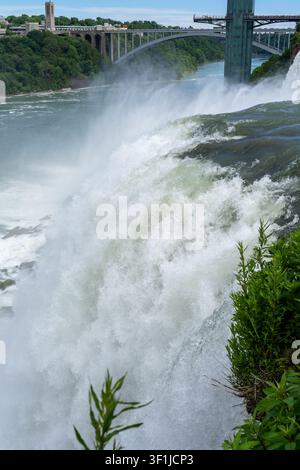 Un primo piano verticale del potente e ruggente acqua bianca delle cascate del Niagara che si riversa in una massiccia cascata. Lo sfondo superiore presenta Foto Stock