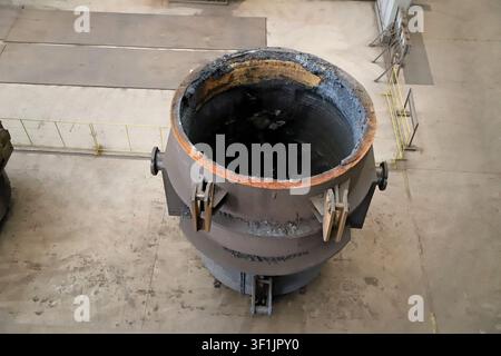 Questa ripresa aerea dall'alto cattura un crogiolo di fusione in una acciaieria, con la parete interna scura e carbonizzata del crogiolo che crea un contrasto visivo netto Foto Stock