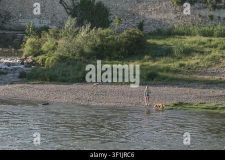 Donna con cane e casa sullo sfondo sulla riva dell'Arno vicino a Firenze, Italia Foto Stock