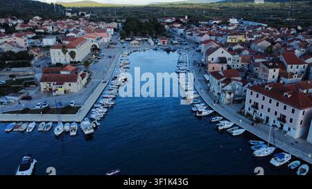 Città costiera di Stari Grad in Croazia, che mostra edifici tradizionali e molte barche ormeggiate nel tranquillo porto Foto Stock