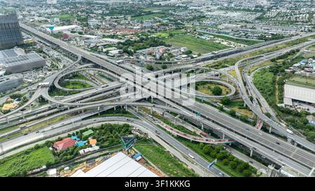 Un punto di vista elevato che cattura il design intricato e il flusso di traffico intenso di un moderno interscambio autostradale a più livelli a Lat Krabang Bangkok, Thailandia. Foto Stock