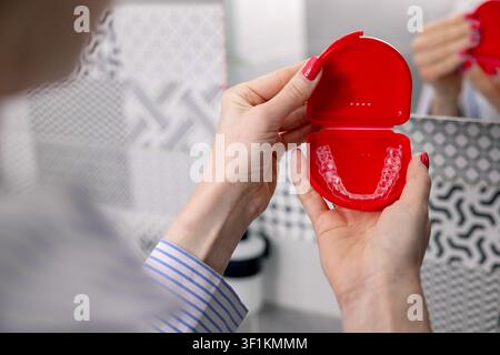 Donna che tiene una scatola con allineatori dentali trasparenti invisibili per la correzione dei denti Foto Stock
