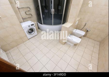 bagno piastrellato con doccia, toilette, bidet e lavatrice Foto Stock