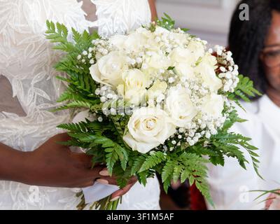 Sposa che tiene un elegante bouquet nuziale di rose bianche e gypsophila con fogliame di felce Foto Stock
