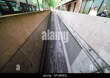 Una vista grandangolare di una rampa in cemento che conduce a un parcheggio sotterraneo a Vancouver, British Columbia, con un autobus cittadino che passa. Foto Stock