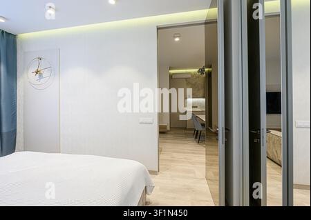 appartamento luminoso e moderno con una vista parziale della camera da letto, un'occhiata nella cucina e ante dell'armadio a specchio Foto Stock