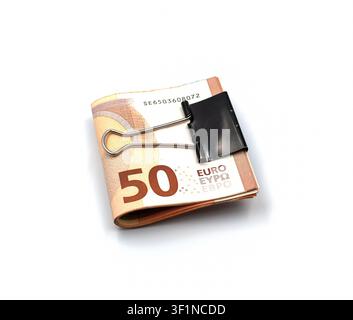 Una pila piegata di banconote da cinquanta euro fissata con una graffetta di metallo nera, isolata su sfondo bianco Foto Stock