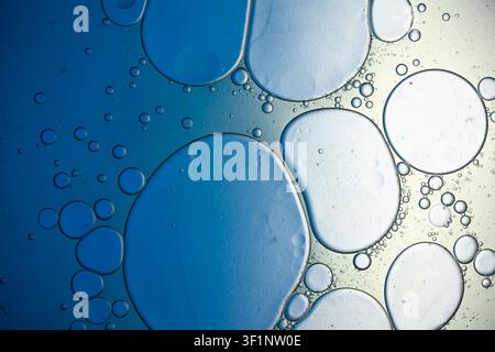 Gocce di olio sulla superficie dell'acqua che creano uno sfondo liquido astratto blu e bianco Foto Stock
