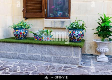 Vasi di fiori in ceramica sul davanzale della finestra di un cortile mediterraneo con piante in vaso colorate e vegetazione Foto Stock