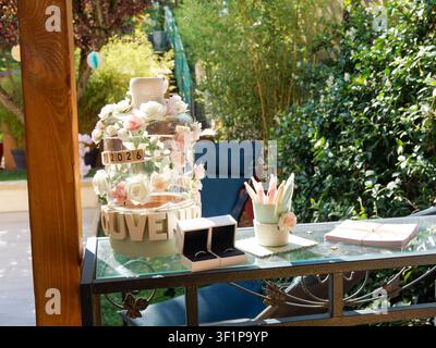 Tavolo per il libro degli ospiti del matrimonio con decorazione floreale e matite colorate in una reception in giardino Foto Stock