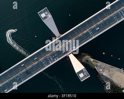 Vista aerea del ponte Bolte con il traffico che scorre lungo l'autostrada a più corsie e una piccola barca che lascia un risveglio nell'acqua sottostante a Docklands, Victor Foto Stock
