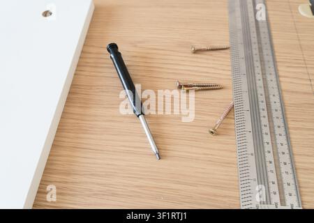 Prima di una pannello di mobili in legno, di una rigla e di una punta da trapano per l'assemblaggio di una panca portaoggetti Foto Stock