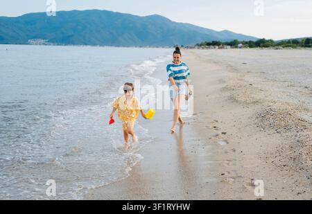 Madre e figlio che corrono insieme su Sunset Beach Foto Stock