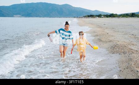 Madre e figlio che corrono insieme su Sunset Beach Foto Stock