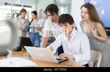 Colleghi che guardano insieme un notebook in ufficio Foto Stock