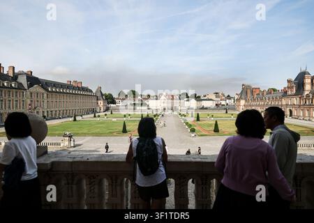 Pechino, Francia. 14 luglio 2026. Turisti visitano il Palazzo di Fontainebleau a Seine-et-Marne, in Francia, mentre il fumo di un incendio boschivo è visibile in lontananza, il 14 luglio 2026. La polizia francese ha detenuto 59 persone in tutto il paese in relazione agli incendi boschivi, compresi due sospetti legati alle fiamme nella foresta di Fontainebleau nel dipartimento di Seine-et-Marne, a sud-est di Parigi, ha detto il ministro dell'Interno francese Laurent Nunez lunedì. L'incendio boschivo nella foresta di Fontainebleau è divampato domenica sera e ha continuato a diffondersi lunedì. Credit: Wu Huiwo/Xinhua/Alamy Live News Foto Stock