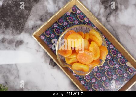 Ciotola di albicocche essiccate su un vassoio colorato in una cucina Foto Stock
