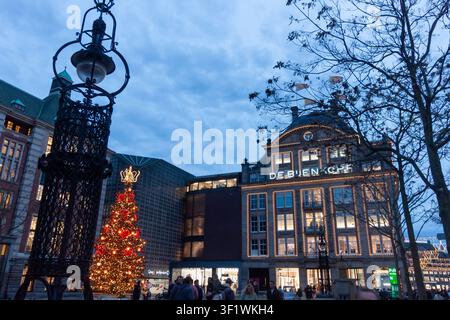 AMSTERDAM, PAESI BASSI - 10 NOVEMBRE 2025: Edificio storico illuminato e albero di Natale decorato in Dam Square ad Amsterdam al crepuscolo Foto Stock