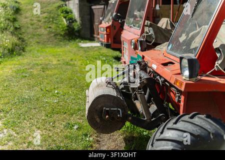 Trattori agricoli alpini rossi parcheggiati sull'erba a Zermatt, Svizzera Foto Stock