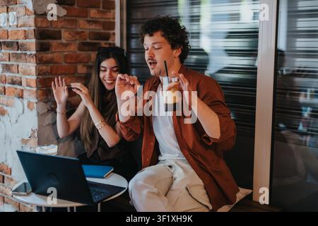 Due studenti delle superiori in un caffè che guardano un laptop e si godono un caffè freddo insieme Foto Stock