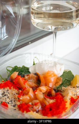 Ciotola di frutti di mare con riso e verdure. Cibo fresco da asporto. Salmone con insalata in primo piano. Menu di un ristorante di frutti di mare. Scatola di frutti di mare con formaggio fresco. Foto Stock
